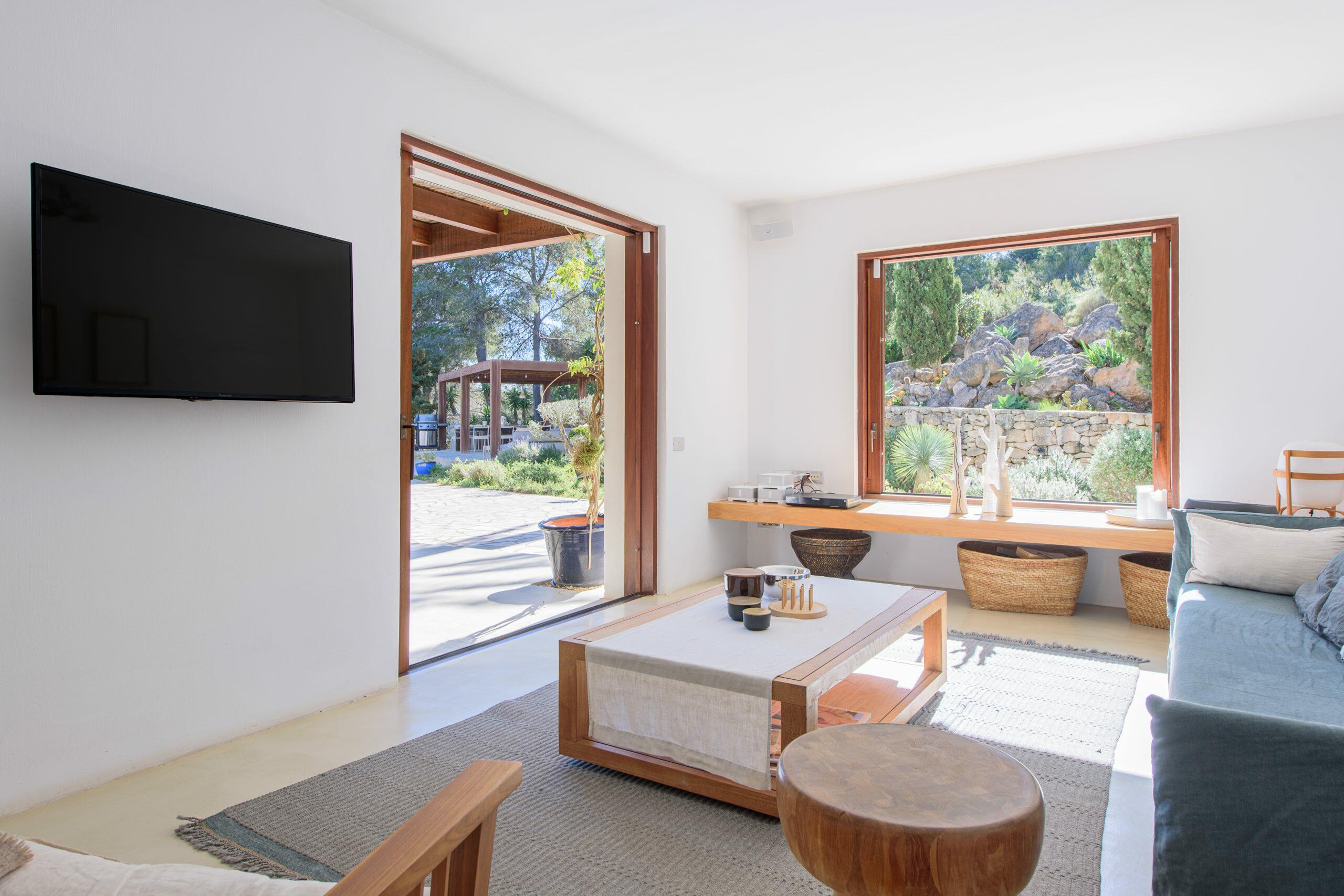 Salon lumineux dans une maison à Ibiza avec de grandes ouvertures sur le jardin et lumière naturelle.