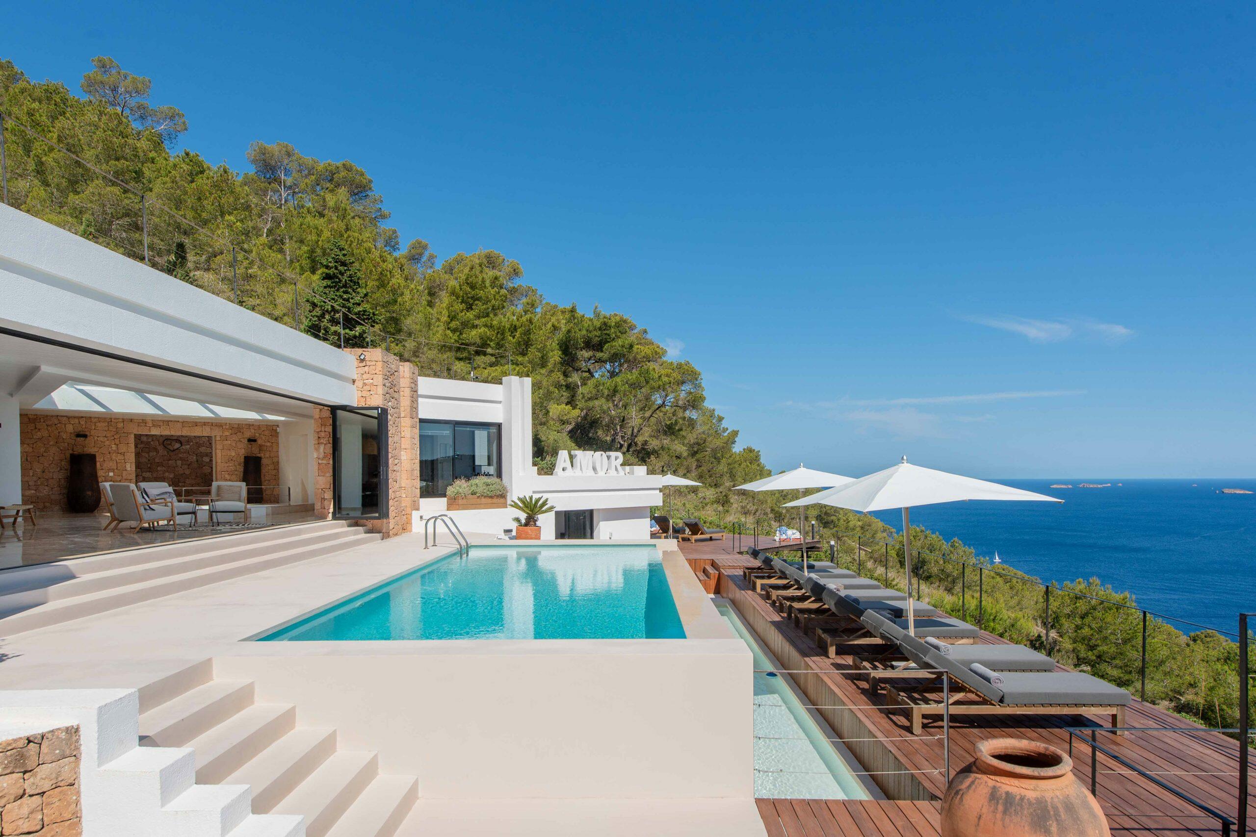 Villa à Ibiza avec piscine, terrasse ensoleillée et vue sur la mer Méditerranée.