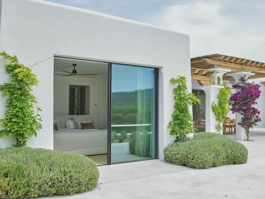 Villa Blakstad à Ibiza avec murs blanchis à la chaux, portes coulissantes en verre, jardin paysager et terrasse couverte.